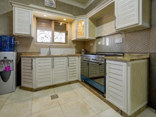 La cuisine est équipée de placards blancs et d'un four avec plaques de cuisson. dans l'établissement ENG-Murjan Apartment, à Aqaba