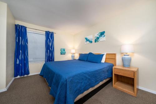 1 dormitorio con cama azul y cortinas azules en Waters Edge 402, en Lincoln City