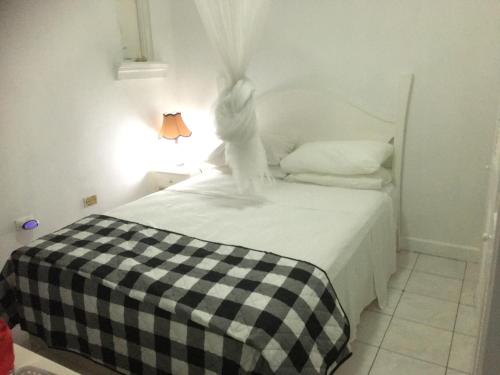 1 dormitorio con 1 cama con manta a cuadros en blanco y negro en The Point, en Orange Bay
