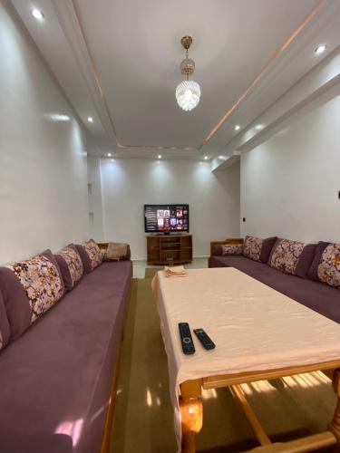 ein Wohnzimmer mit einem großen Sofa und einem TV in der Unterkunft Appartement avec suite parentale in Mohammedia