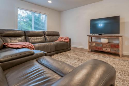 a living room with a leather couch and a flat screen tv at Hideaway in Seaside in Seaside