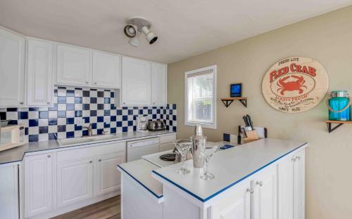 uma cozinha com armários brancos e azulejos azuis e brancos em Seas the Day em Lincoln City