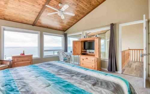 een slaapkamer met een bed, een tv en ramen bij Seas the Day in Lincoln City