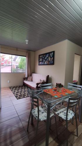 uma sala de estar com uma mesa e cadeiras e um sofá em Casa completa com 2 quartos de casal em Torres em Torres