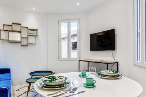 un salon blanc avec une table et une télévision dans l'établissement Cozy apartment near the beach, à Antibes