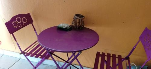 einem lila Tisch mit zwei Stühlen und einer Blume darauf in der Unterkunft Tropical cocoon in Kourou