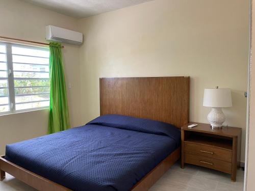 Woods的住宿－Poinciana Villas，一间卧室设有蓝色的床和窗户。
