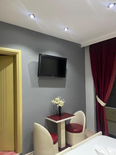 een kamer met een tafel en een tv aan de muur bij Hotel Selfo in Gjirokastër