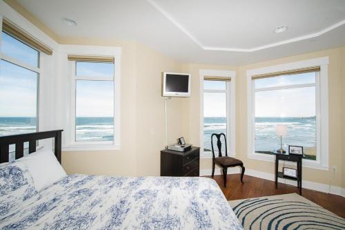 a bedroom with a bed and windows with the ocean at Michael's Beach Place @ Shoreline Ridge in Newport
