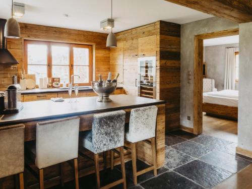 a kitchen with wooden walls and a large island with chairs at Chalet-Apartment Alpenrose am Lift in Kirchberg in Tirol