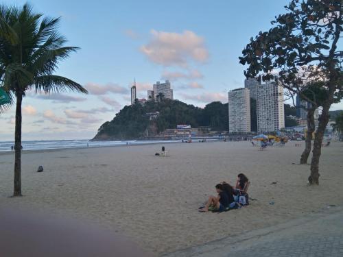 een groep mensen in het zand op een strand bij 2 Qtos C Vista ao Mar - A 200 metros do IlhaPorchat in São Vicente