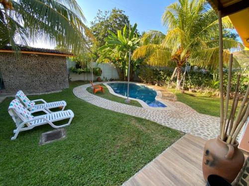 a yard with two chairs and a swimming pool at Rancho Pitas in Nanastepeque