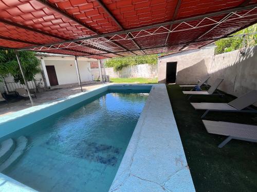a swimming pool with lounge chairs and an umbrella at Flores Condominios Depa Rosa in Álamos