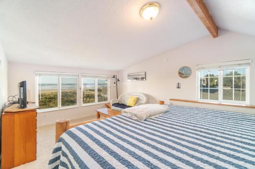 a bedroom with a blue and white striped bed and windows at Rockaway Beachhouse in Rockaway Beach