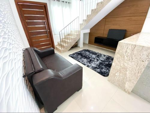 a living room with a leather couch and a staircase at Apartamentos Villa dos Diamantes in Porto Seguro