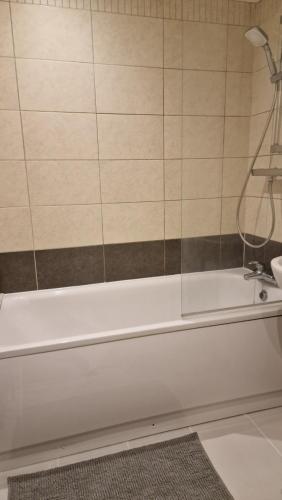 a white bath tub with a shower in a bathroom at London City Stay in London
