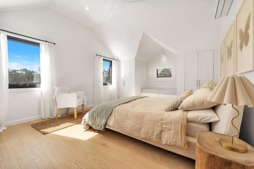 - une chambre blanche avec un grand lit et une chaise dans l'établissement Wembley Cottage, Southern Highlands, à Berrima