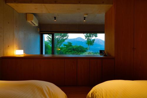 a bedroom with a window with a view of a mountain at Ryokan Konomama in Minami Aso