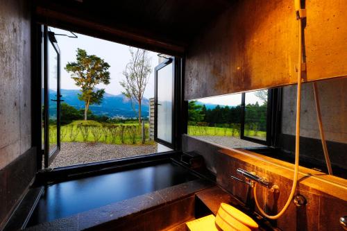 a bathroom with a window with a view of a mountain at Ryokan Konomama in Minami Aso