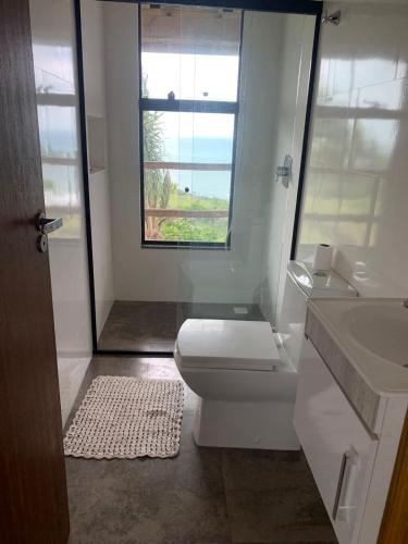 a bathroom with a toilet and a sink and a window at Casa do Morro in Praia do Rosa