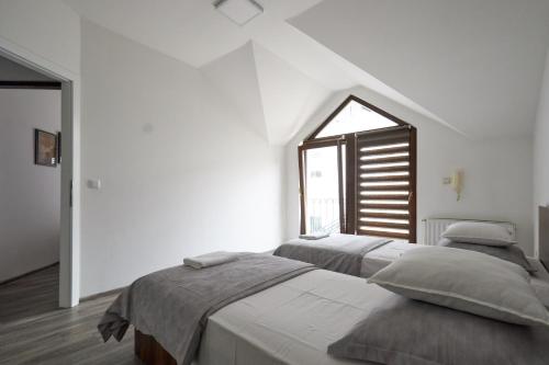 two beds in a white room with a window at Vila Selma in Sarajevo