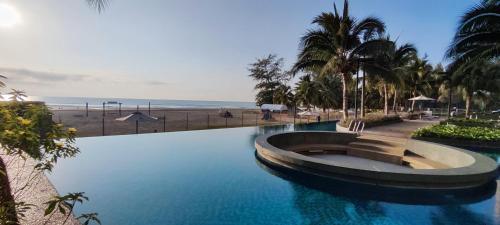 a swimming pool next to a beach with palm trees at TIMURBAY KUANTAN -BEACHFRONT PARADISE GETAWAY in Kuantan