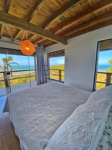 a bedroom with a bed with a view of the ocean at Casa do Morro in Praia do Rosa