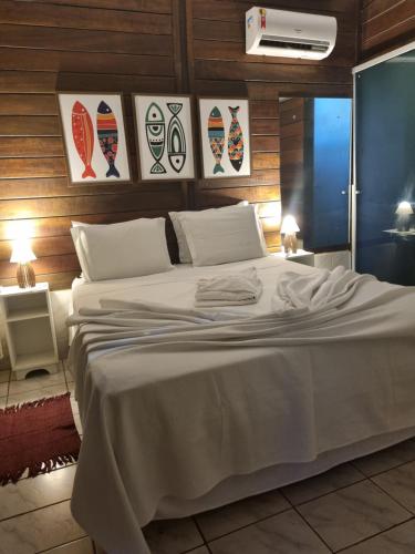 a bedroom with a large white bed with pictures on the wall at Vila Mar in Fernando de Noronha