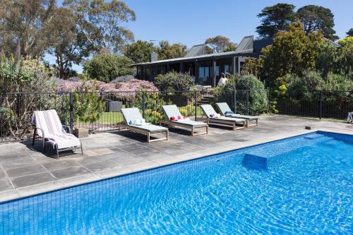 Una piscina con tumbonas al lado de una casa. en Honeysuckle House, en Shoreham