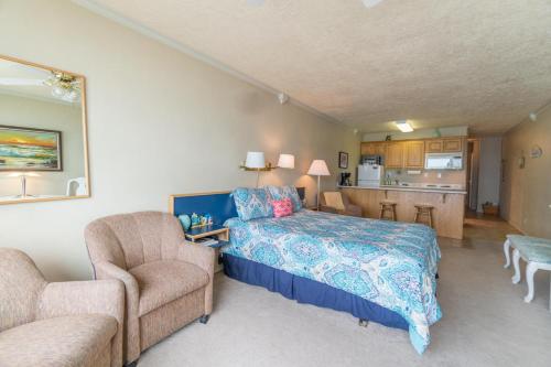 a bedroom with a bed and two chairs and a kitchen at Sea Gypsy 318 in Lincoln City