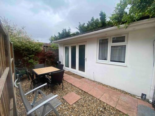 a patio with a table and chairs in front of a house at Garden Studio Escape Open-Plan Comfort & Outdoor Space in London