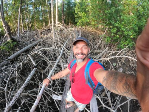 een man die door een touwbrug in een bos loopt bij CARABAO Hostel in Soure