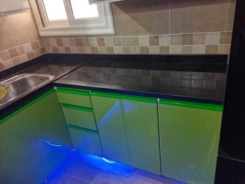 a kitchen with green and blue cabinets and a sink at شقه فندقية 3غرف بمدينتي امام كرافت زون01117805968 in Madinaty
