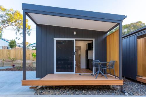 a small house with a deck and a table at Poinciana at Cooee Bay in Yeppoon