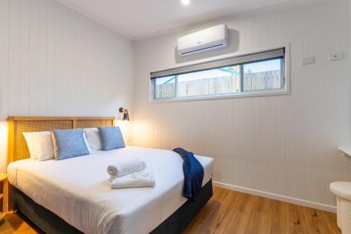 a bedroom with a bed and a window at Poinciana at Cooee Bay in Yeppoon