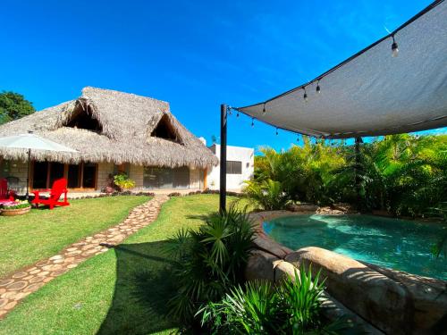 um resort com uma piscina e um telhado de palha em Cabana para 6 con Alberca a solo 3 min de la Playa de Chacala Nayarit em Chacala