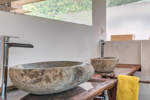 łazienka z dużą kamienną umywalką na drewnianym blacie w obiekcie Splendido attico per chi ama escursioni nella natura w mieście Grono