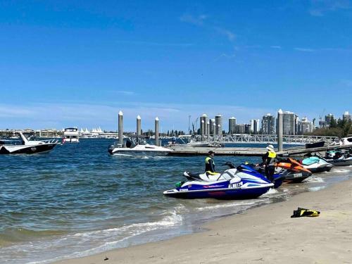 a group of people standing on a beach with boats at Broadwater Parklands Paradise in Gold Coast