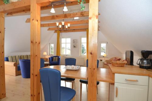 eine Küche und ein Esszimmer mit einem Holztisch und blauen Stühlen in der Unterkunft Alte Büdnerei - Apt. 02 in Ostseebad Sellin