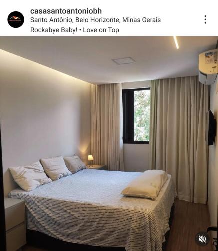 a bedroom with a bed with white sheets and a window at Hidro, piscina aqc, próx savassi in Belo Horizonte