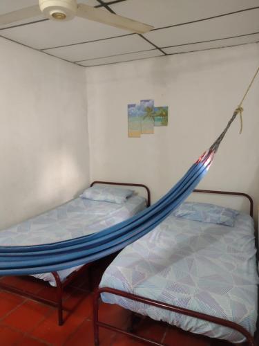 two beds in a room with a hammock at Hospedaje Doña Victoria in Santa Marta