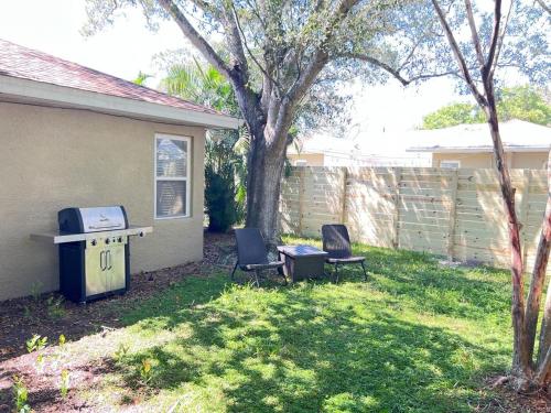 a yard with two chairs and a grill and a house at Hostal Sky Crest in Clearwater