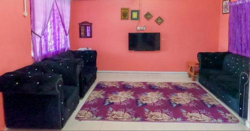 ein Wohnzimmer mit zwei schwarzen Stühlen und einem TV in der Unterkunft Teres luas & selesa, dekat shopping mall, UMT in Kuala Terengganu