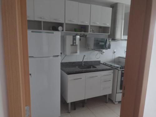 a kitchen with white cabinets and a white refrigerator at O melhor e + aconchegante AP de SPA (custo/benefício) in São Pedro da Aldeia