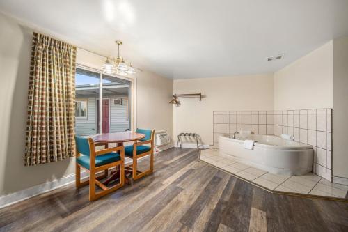 ein Bad mit einer Badewanne, einem Tisch und Stühlen in der Unterkunft Thumb Heritage Inn in Sandusky