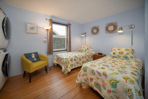 a bedroom with two beds and a chair and a window at Barefoot Bungalow in Seaside