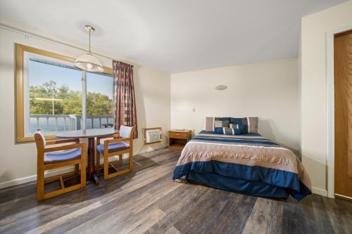 Schlafzimmer mit einem Bett, einem Tisch und einem Fenster in der Unterkunft Thumb Heritage Inn in Sandusky
