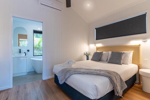 a bedroom with a bed and a bathroom with a tub at Poinciana at Cooee Bay in Yeppoon