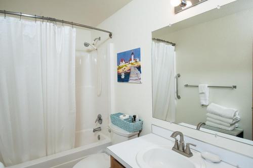 a bathroom with a sink and a shower and a mirror at Family Tides in Seaside in Seaside