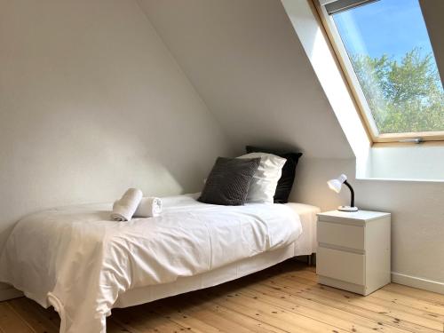 a bedroom with a white bed and a window at Lovely Two Story House in Odense